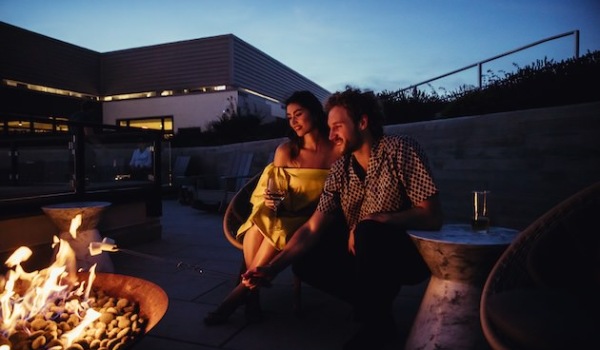 Couple sitting in front of a fire pit at dusk